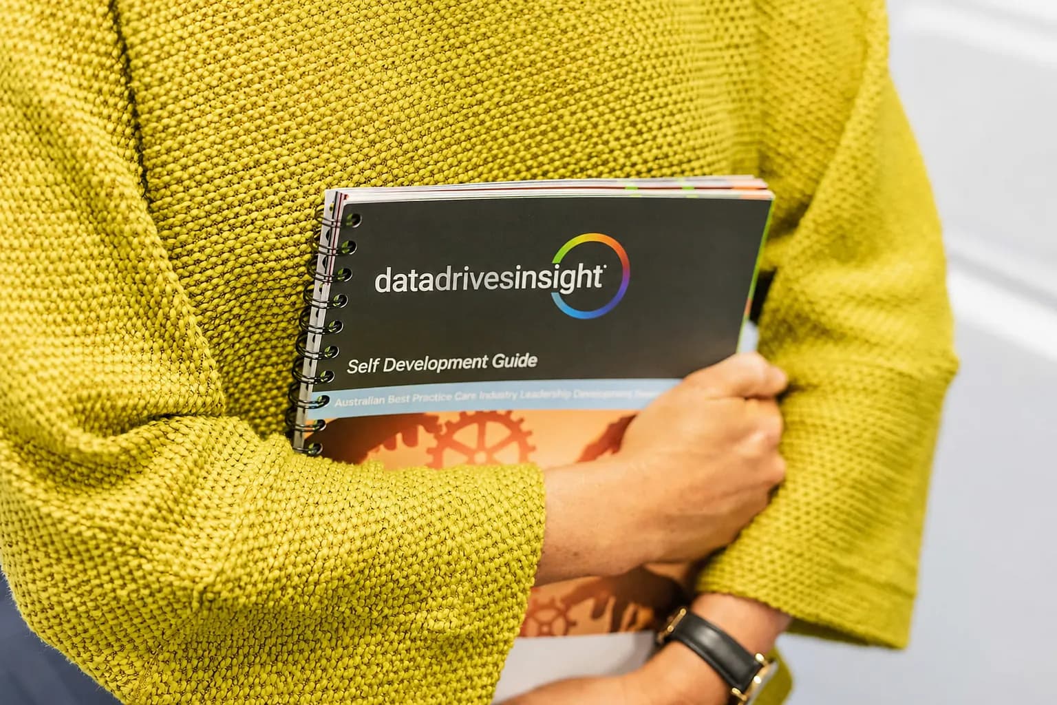 a lady in a yellow sweater holding a DDI booklet